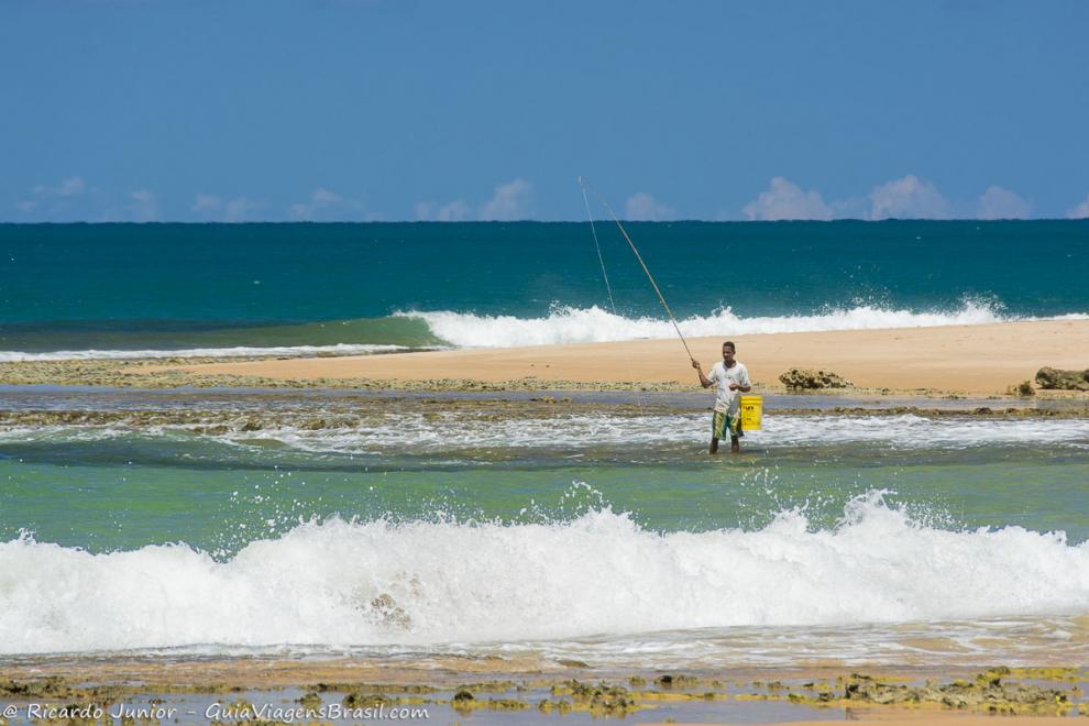 Imagem das espumas brancas como neve e pescador na Praia da Bombaça.